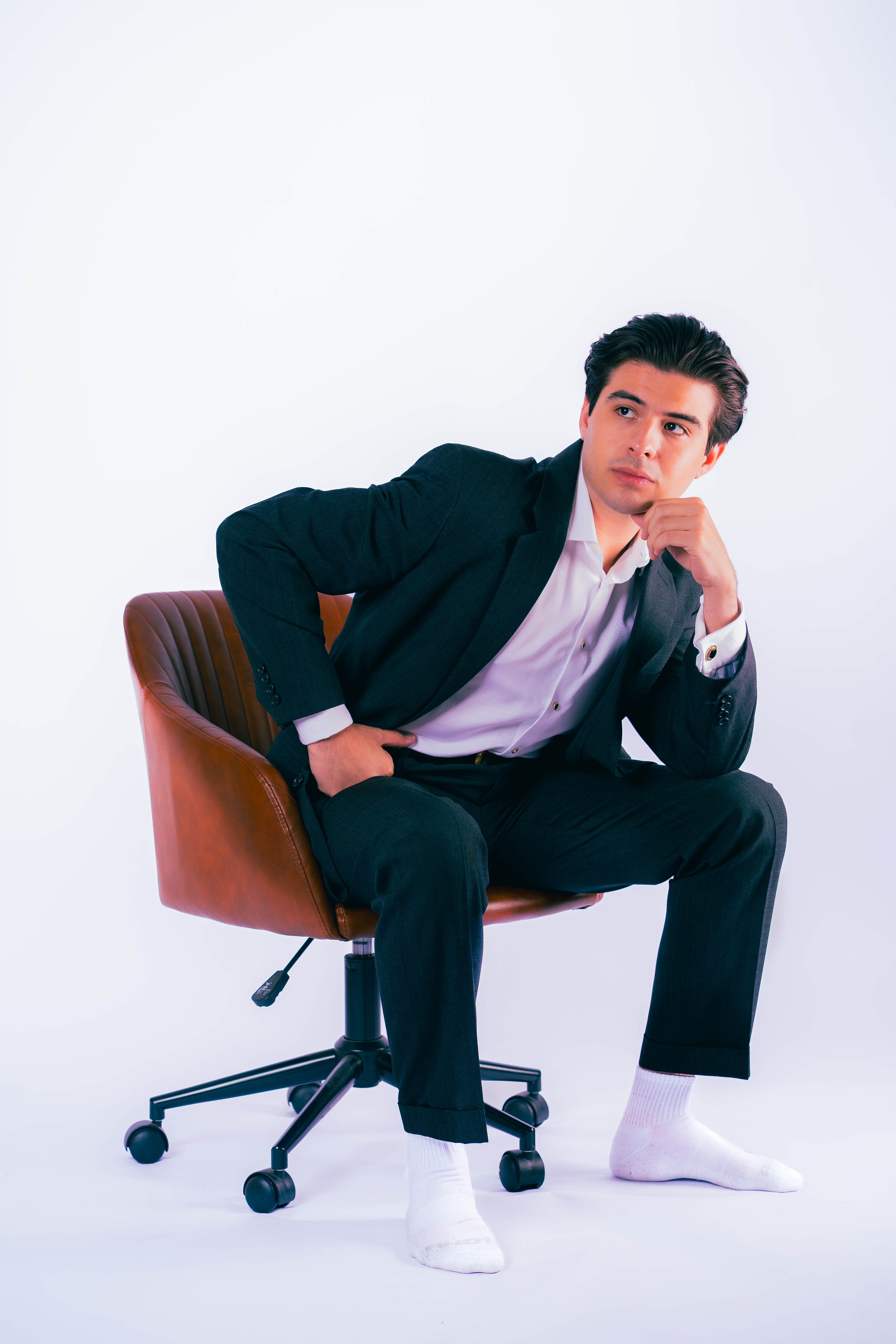 The photographer — portrait in a charcoal suit, seated
