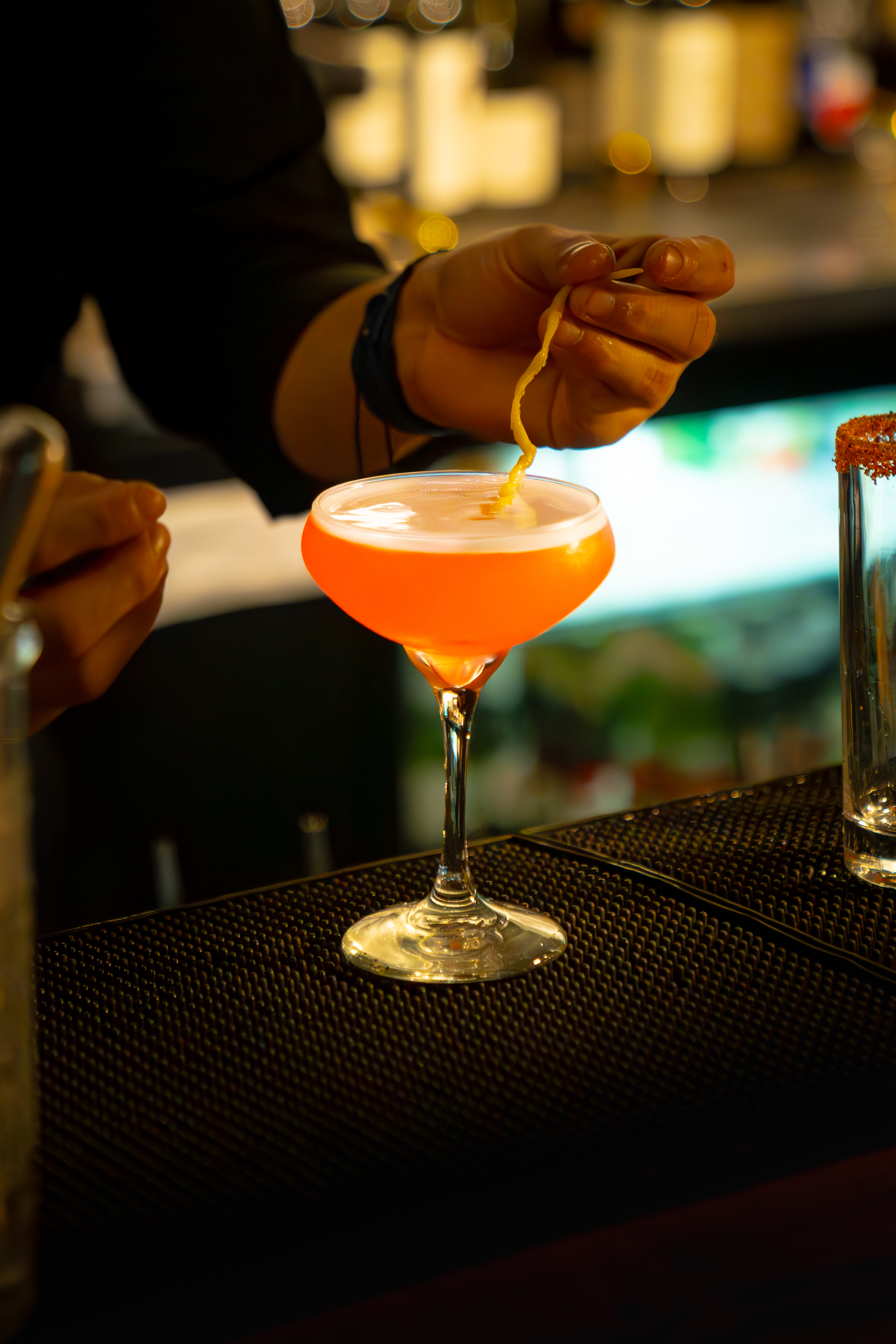 Bartender garnishing a coupe of orange cocktail at The Bunker