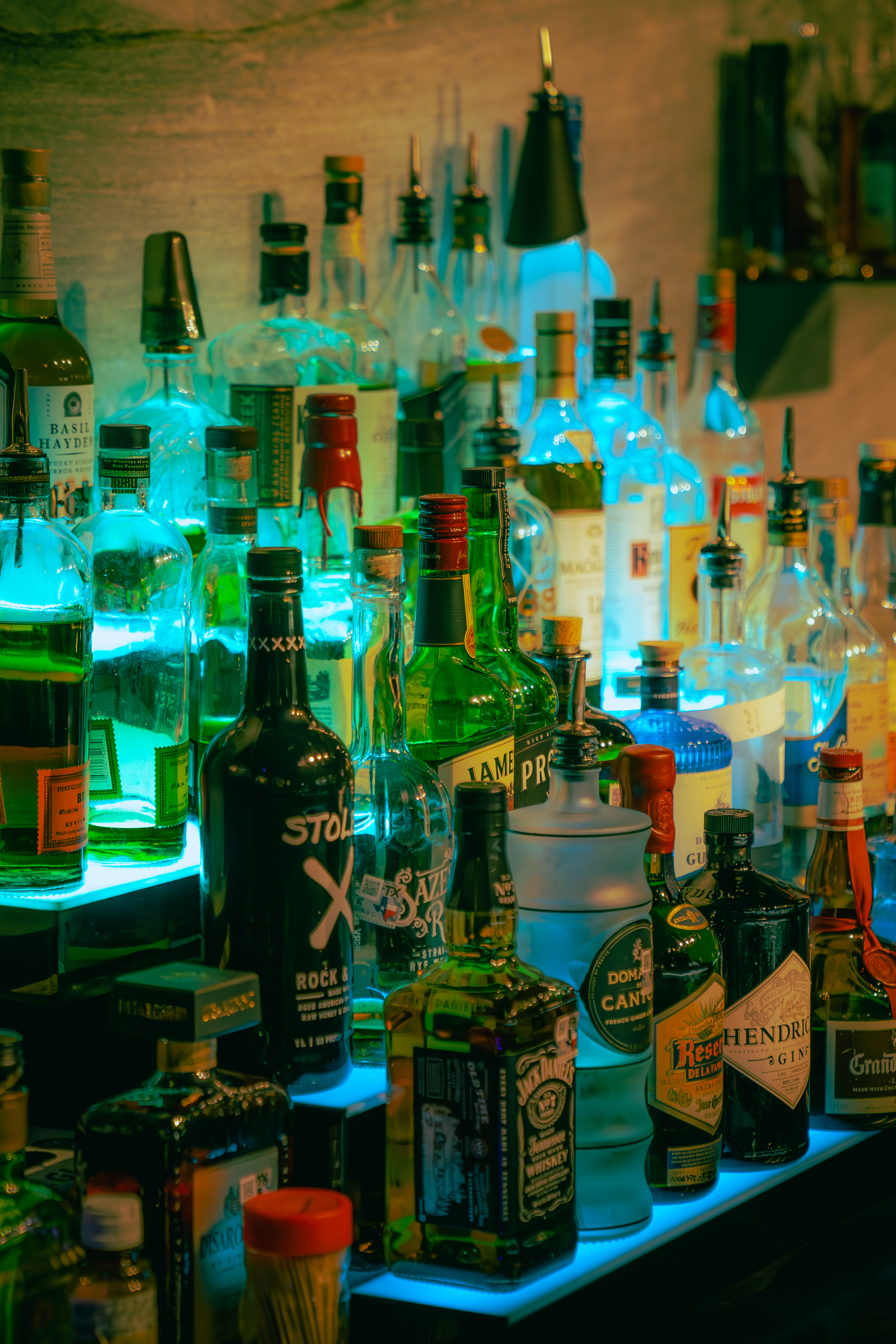 Backlit liquor bottles glowing teal and blue on The Bunker backbar