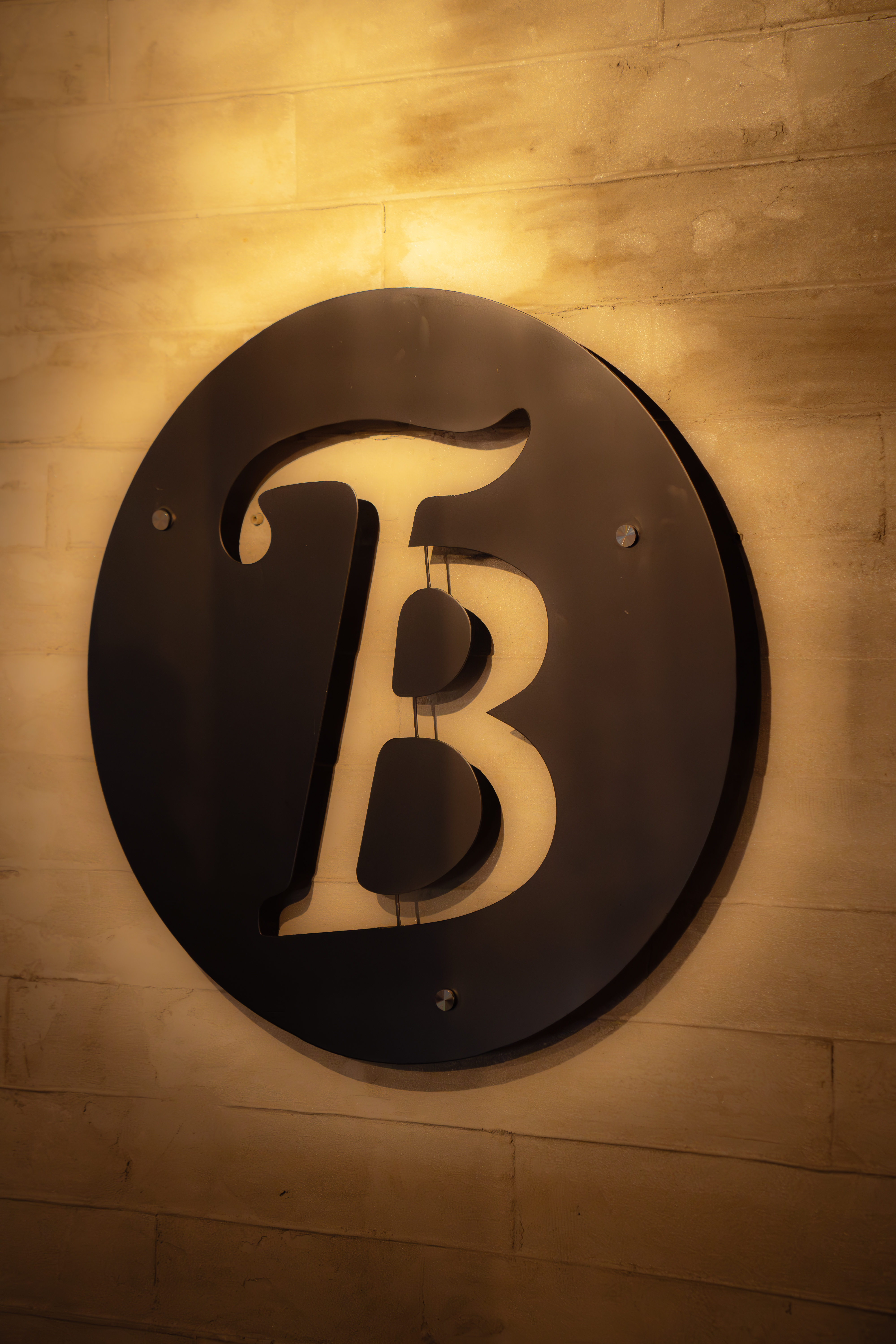 The Bunker circular B logo backlit on a brick wall