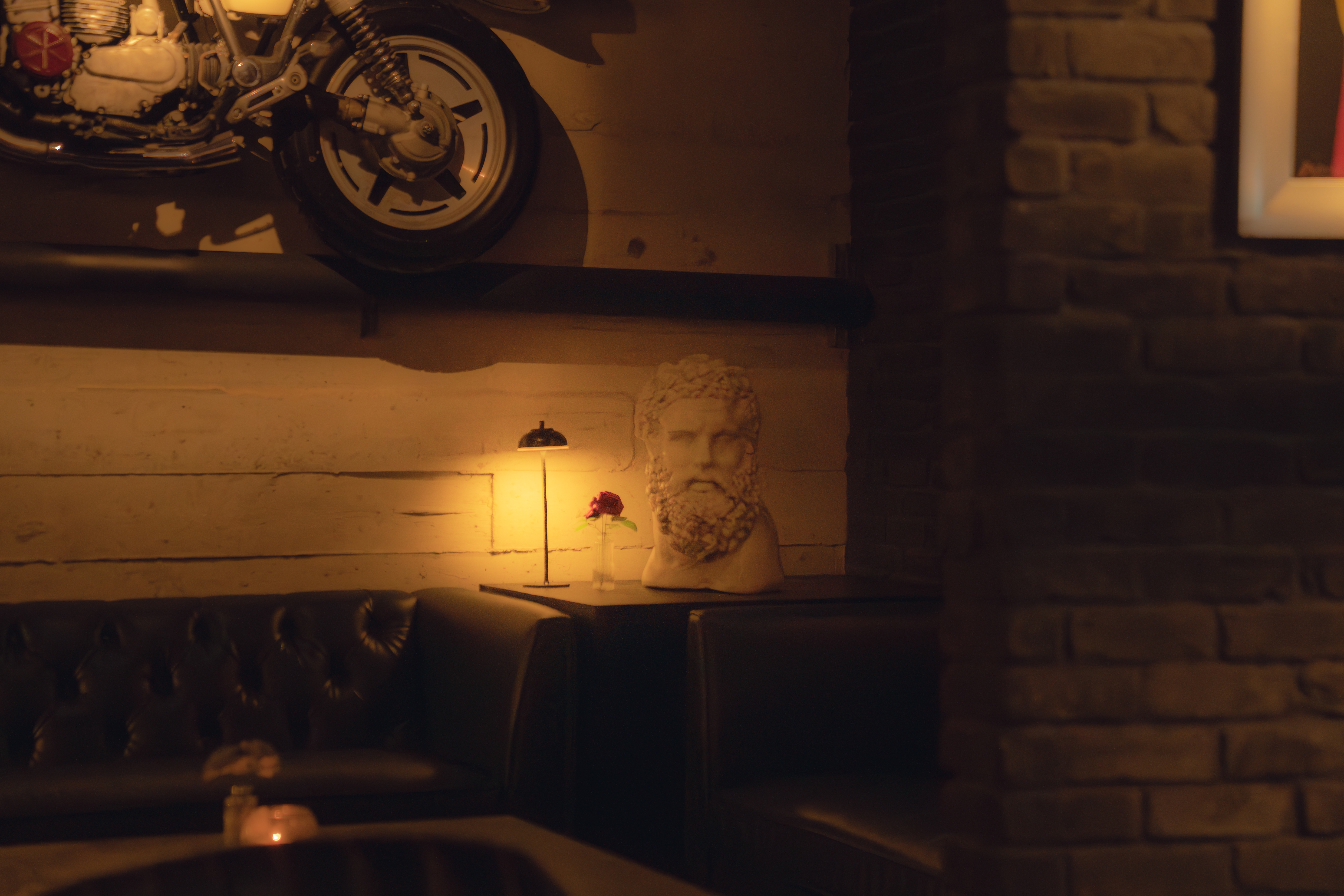 Lounge corner at The Bunker with mounted motorcycle, marble bust and warm lamp