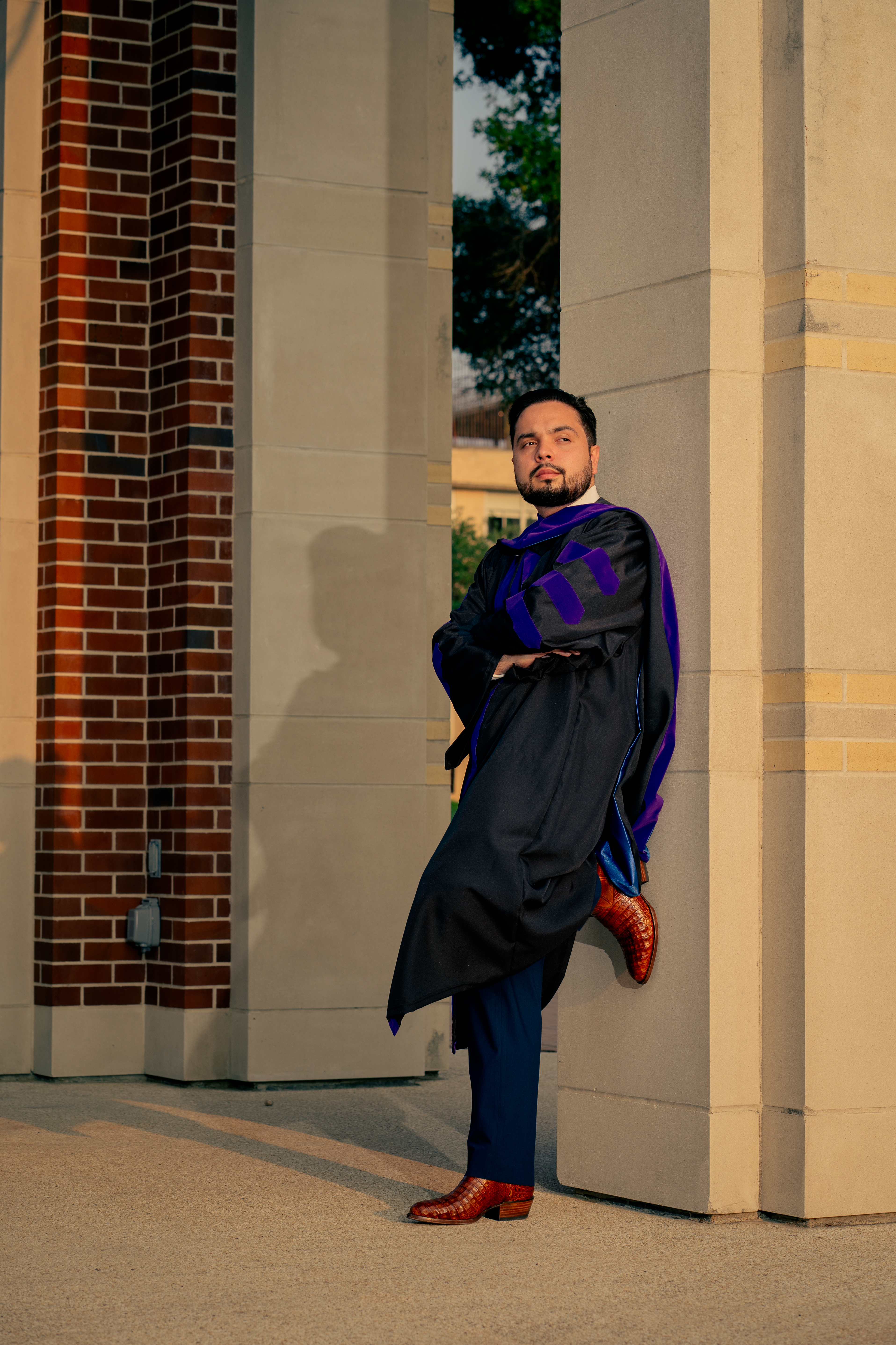 Graduate posing with foot against a column and arms crossed in doctoral gown, St. Mary's University