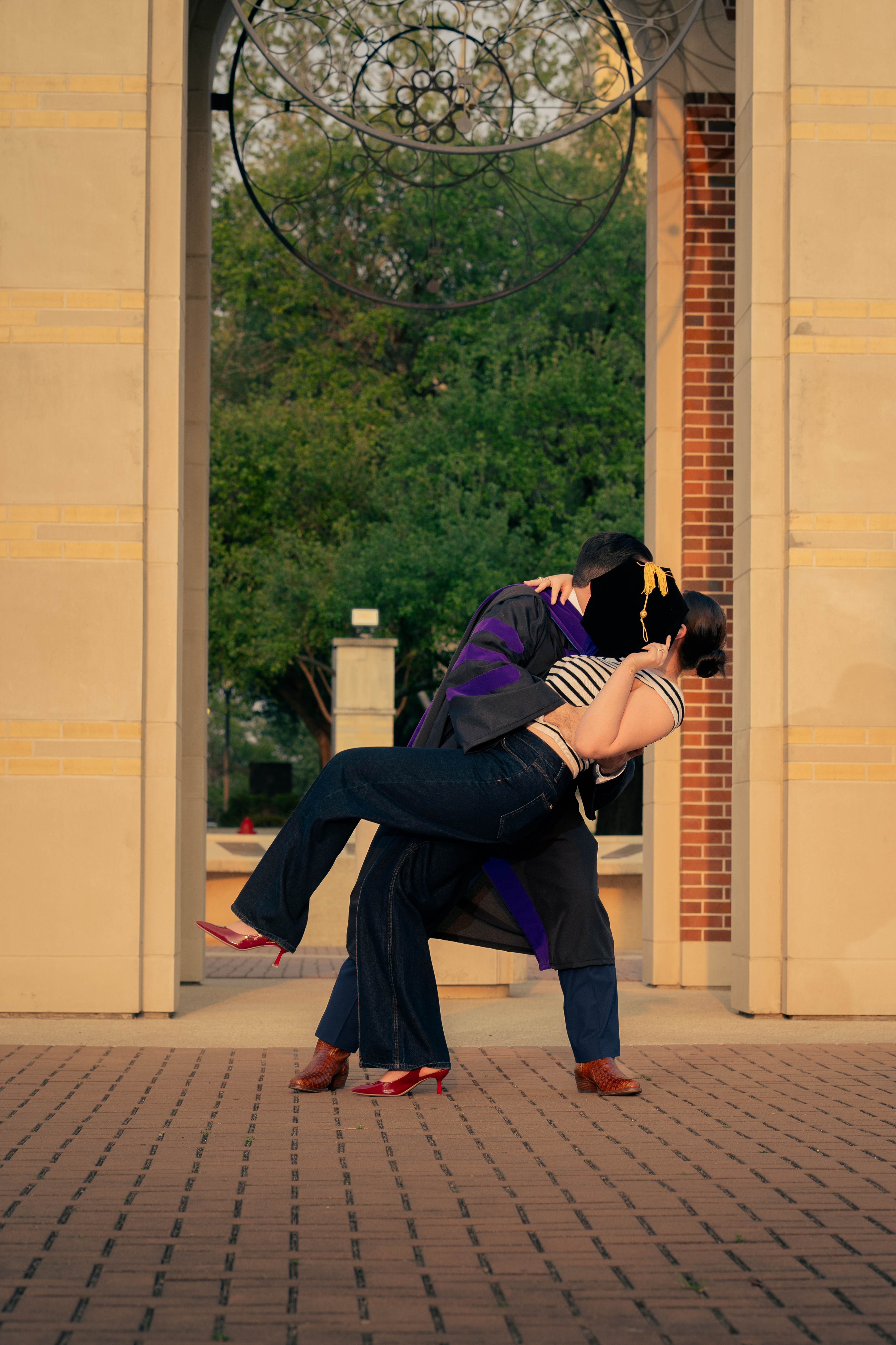 Graduate dipping and kissing their partner under the campus archway, St. Mary's University