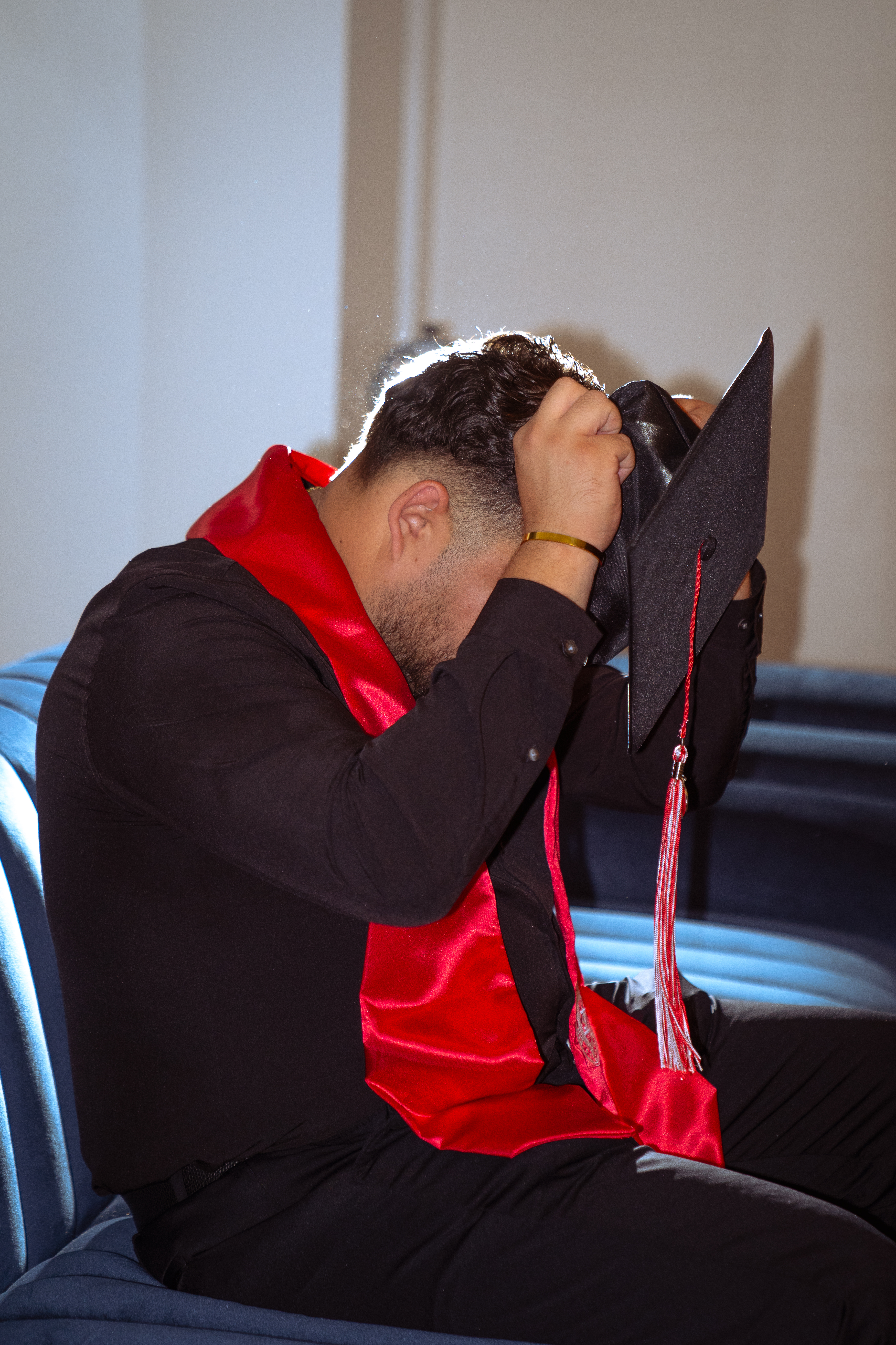 Graduate in cap and red stole leaning on the railing of an ornate historic staircase, downtown San Antonio