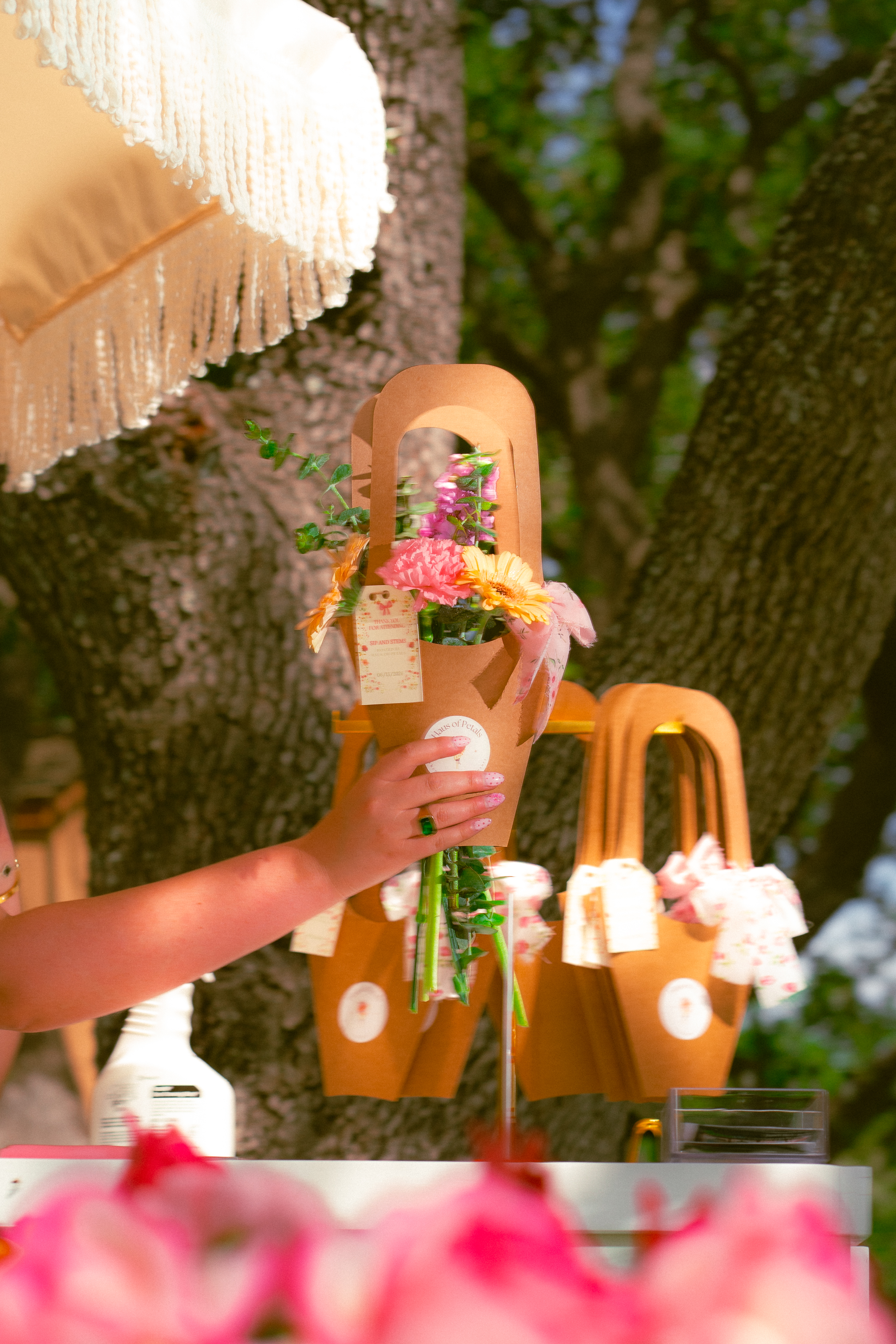 Kraft-paper flower bag with a bright bouquet held up under a tree, Haus of Petals