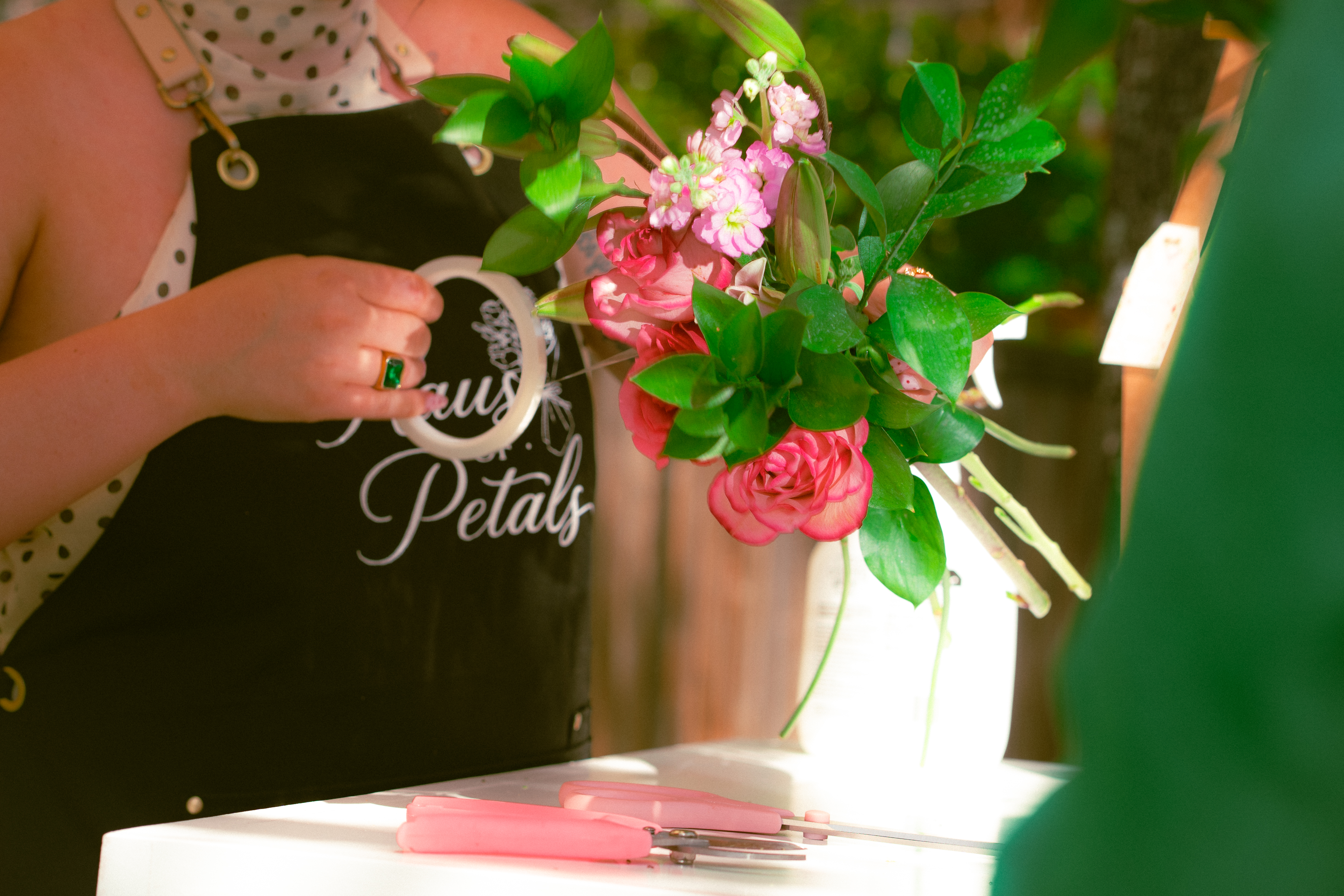 Florist in a Haus of Petals apron assembling a hand-tied arrangement