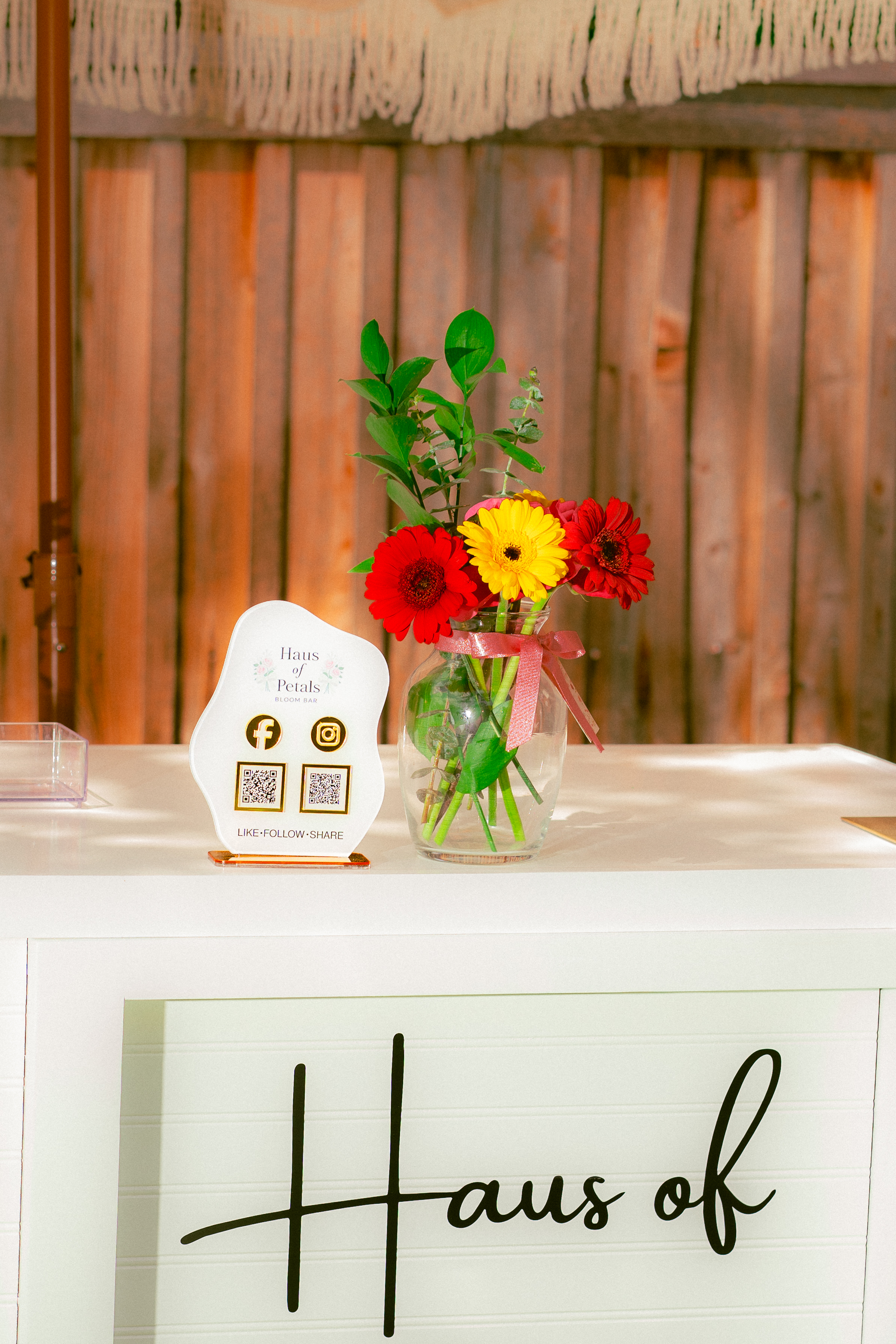 Haus of Petals QR follow sign and gerbera vase on the bloom bar counter
