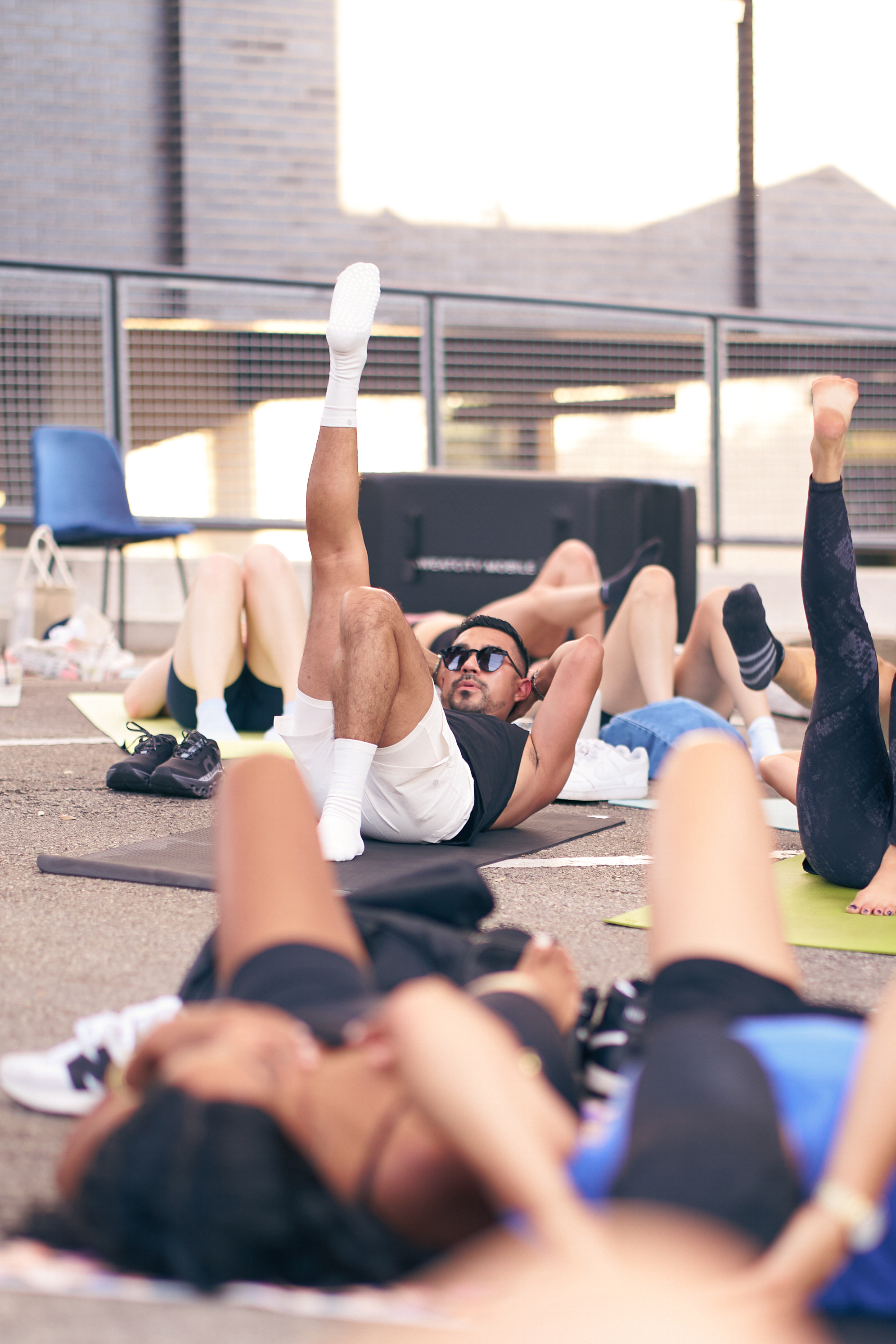 Group doing leg raises on mats during the rooftop pilates session, Native Roots event