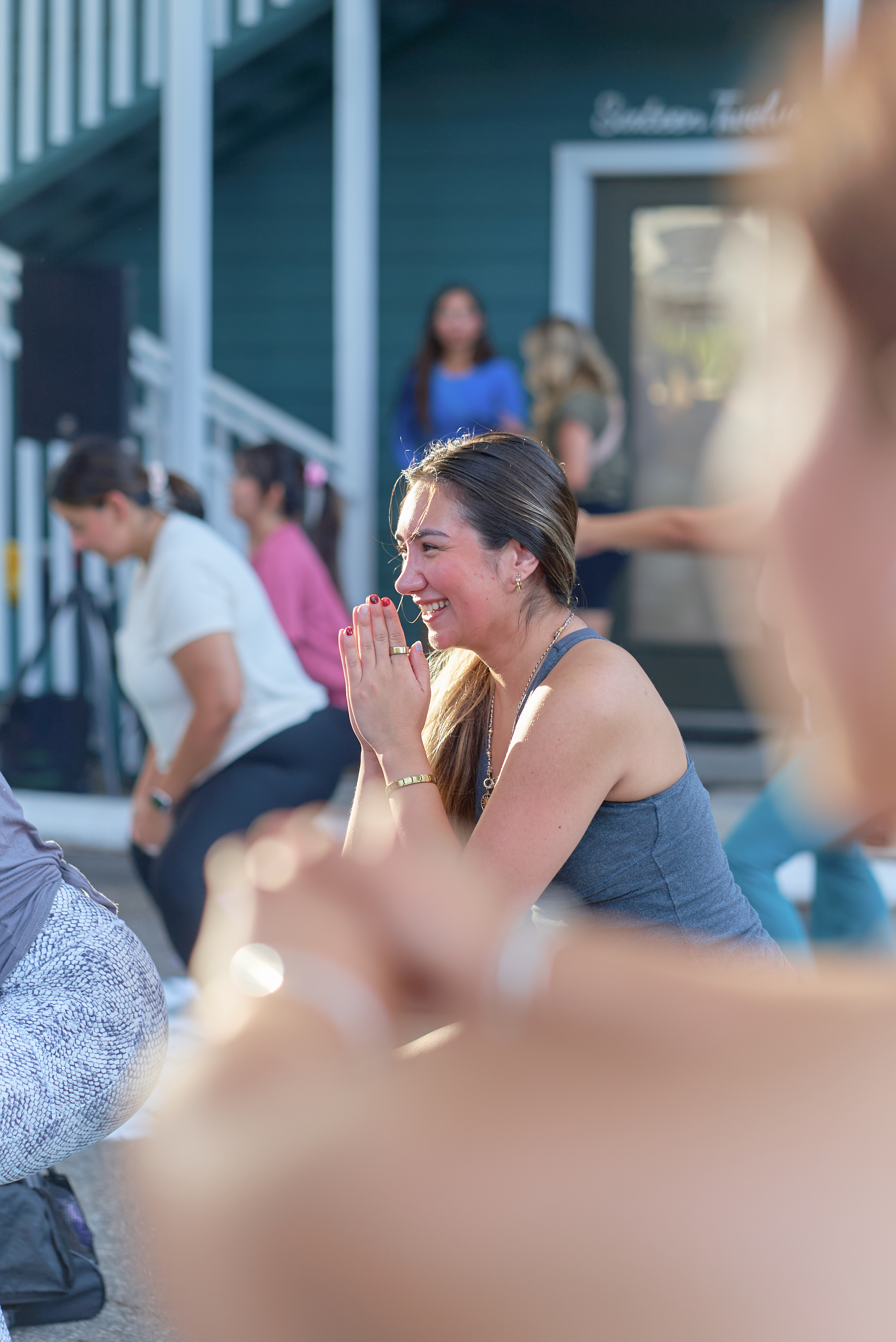 Attendee smiling with hands together during the outdoor class at the Native Roots event
